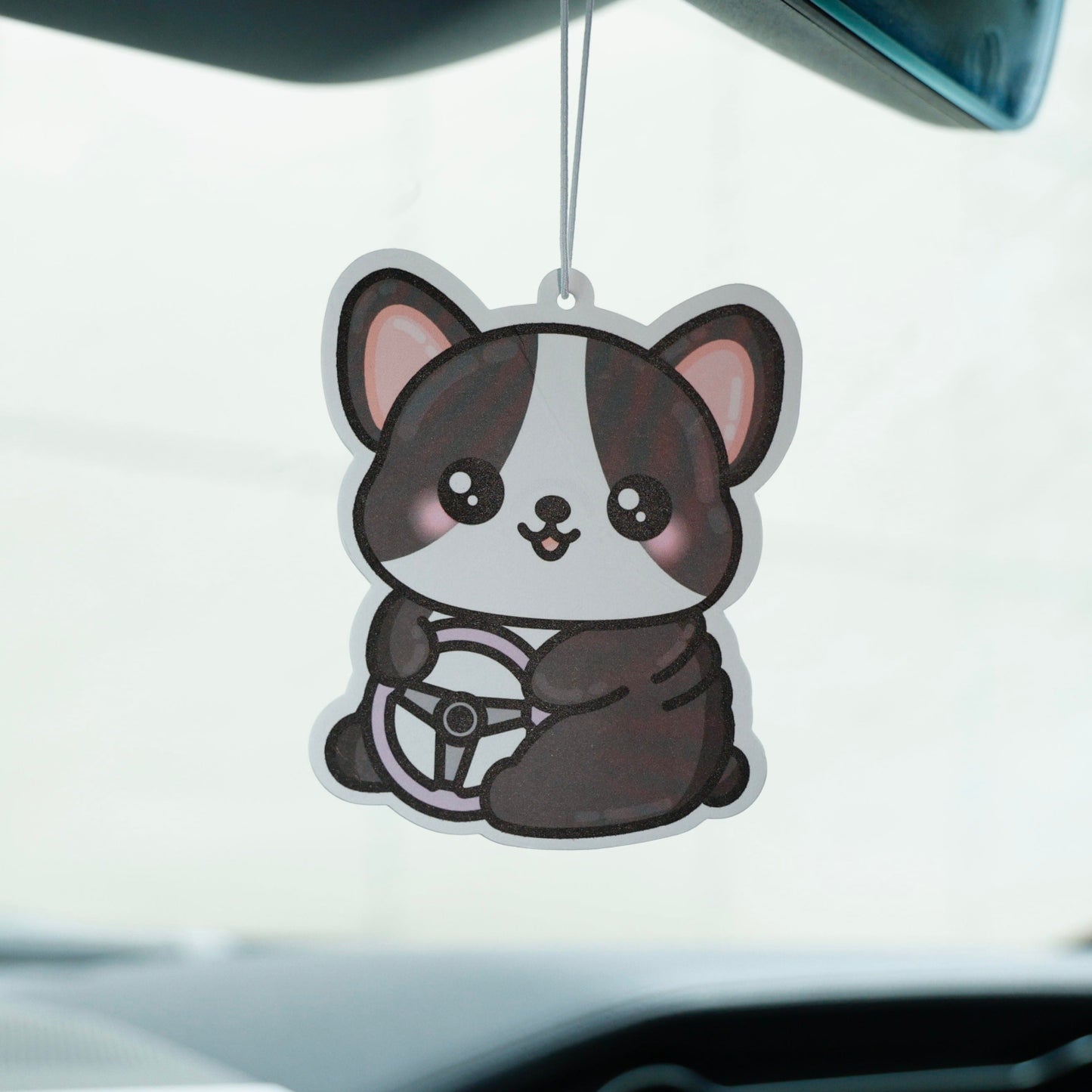 Car air freshener shaped like a cartoon dog hanging from a car's rearview mirror.