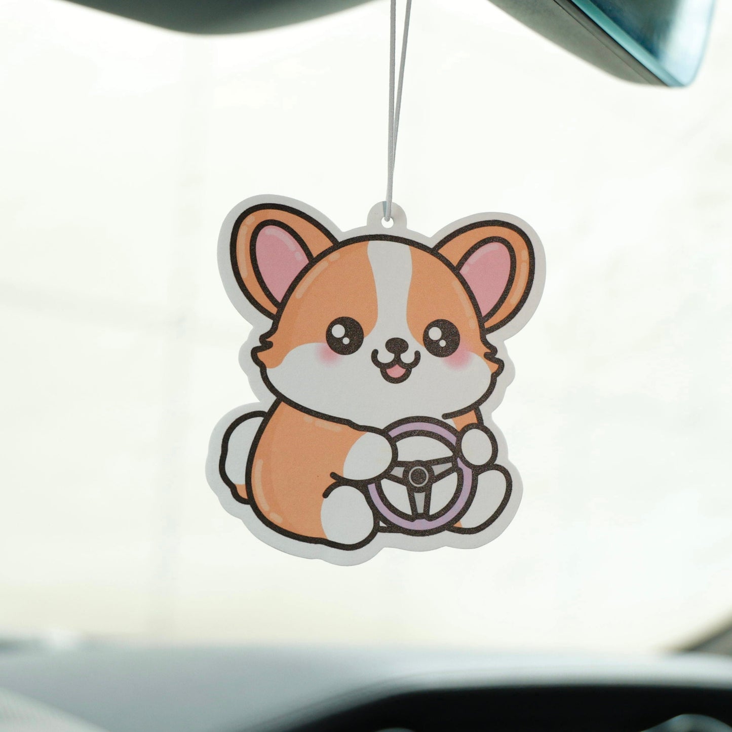Car air freshener shaped like a cartoon dog hanging from a car's rearview mirror.