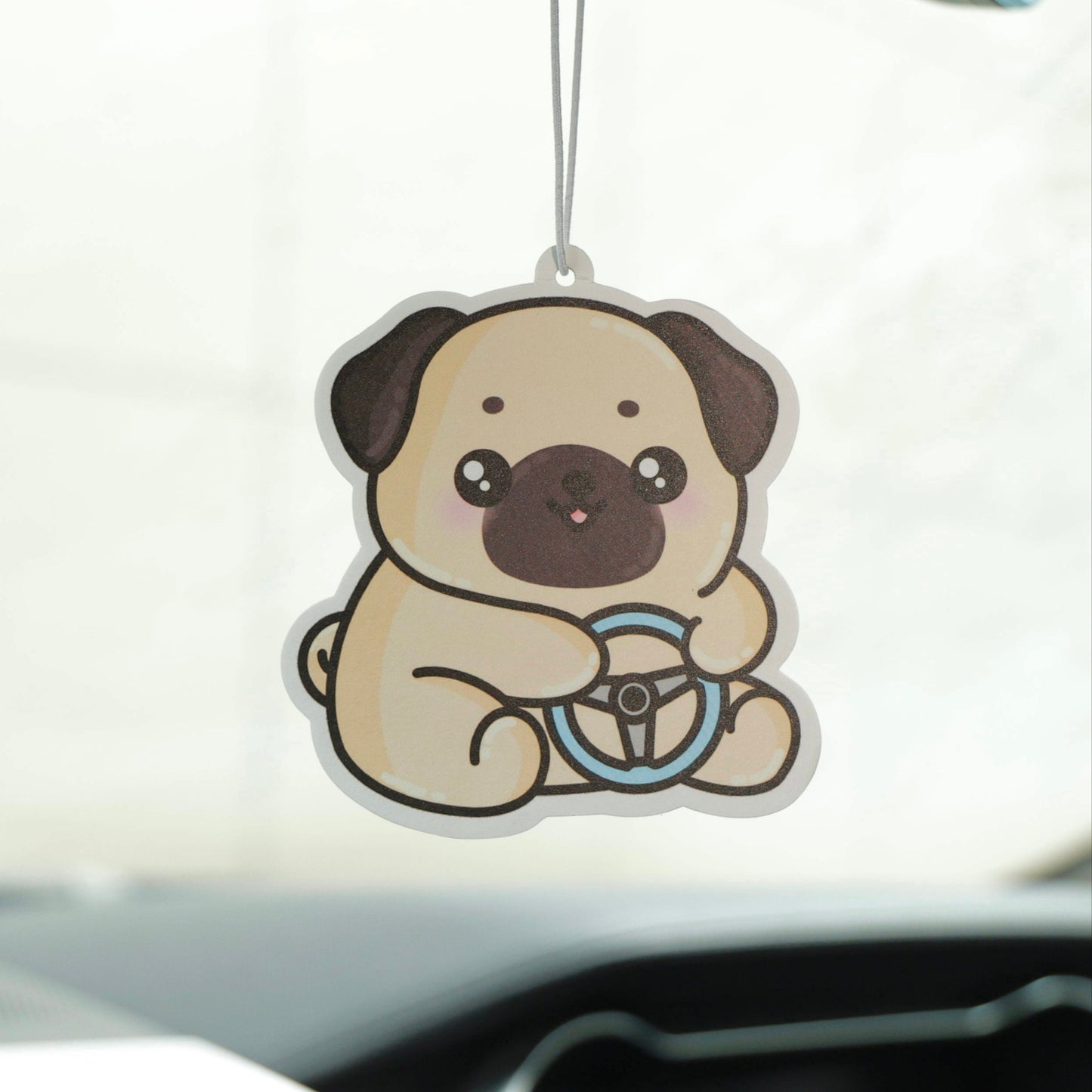 Car air freshener shaped like a pug hanging from a car's rearview mirror.