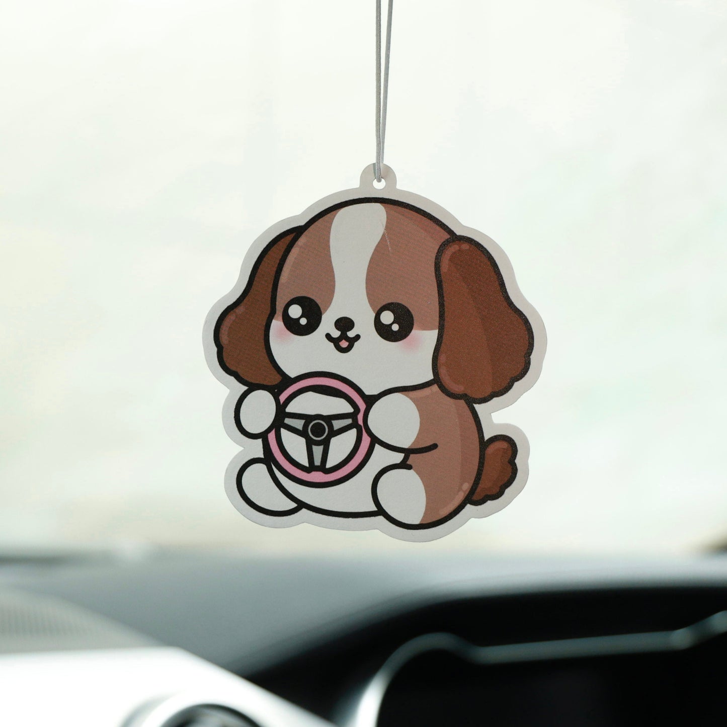 Car air freshener shaped like a cartoon dog hanging from a car's rearview mirror.