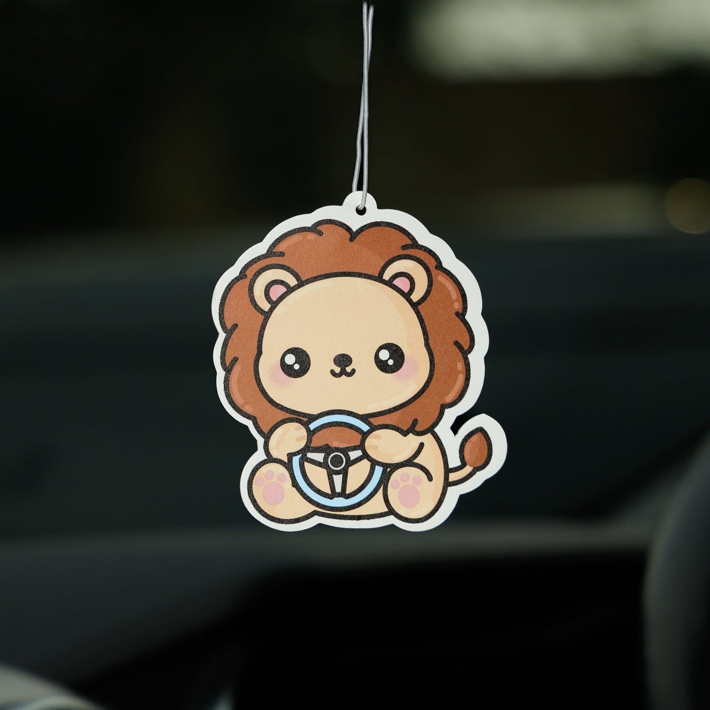 Car air freshener shaped like a lion hanging from a car's rearview mirror.