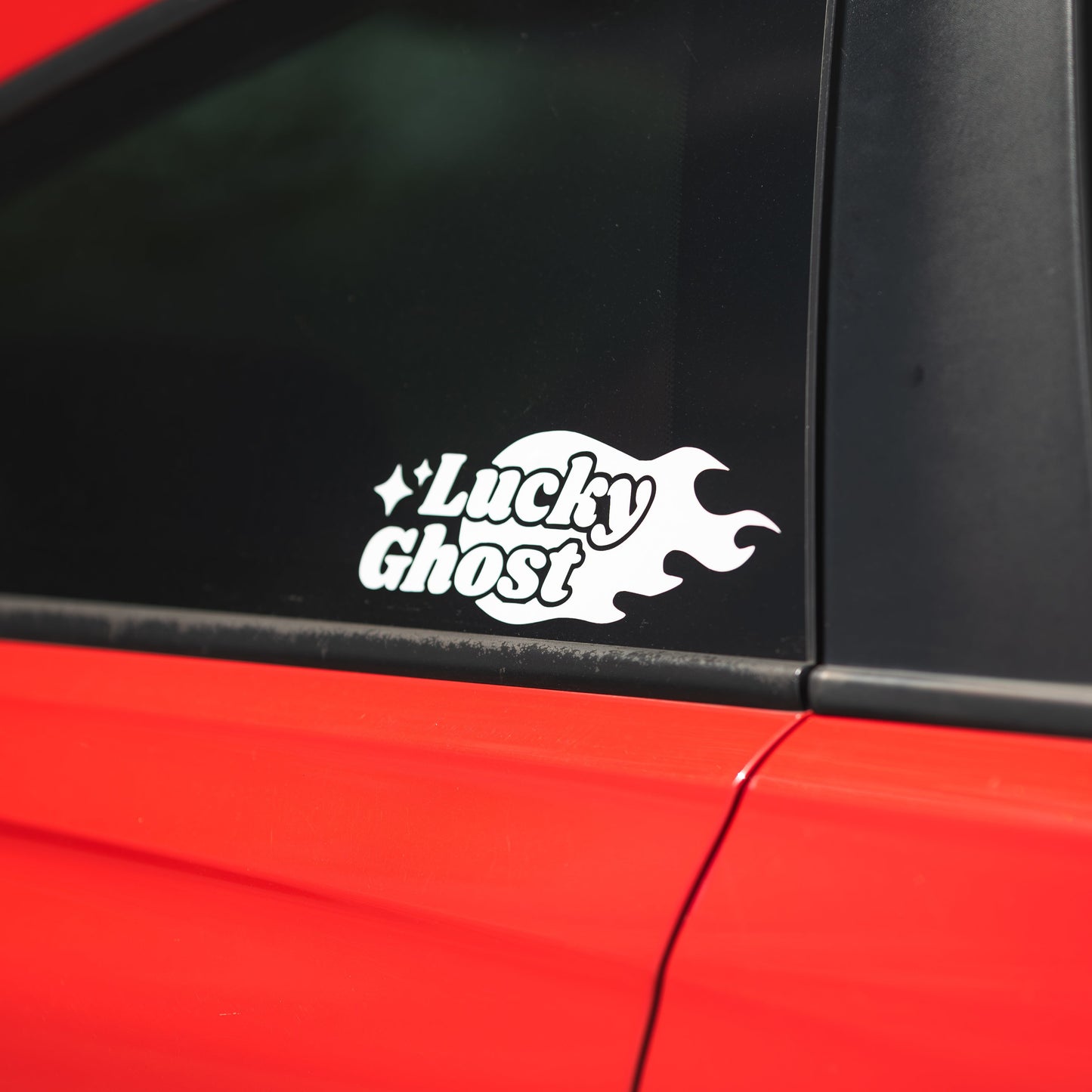 White 'Lucky Ghost' decal on a red car window