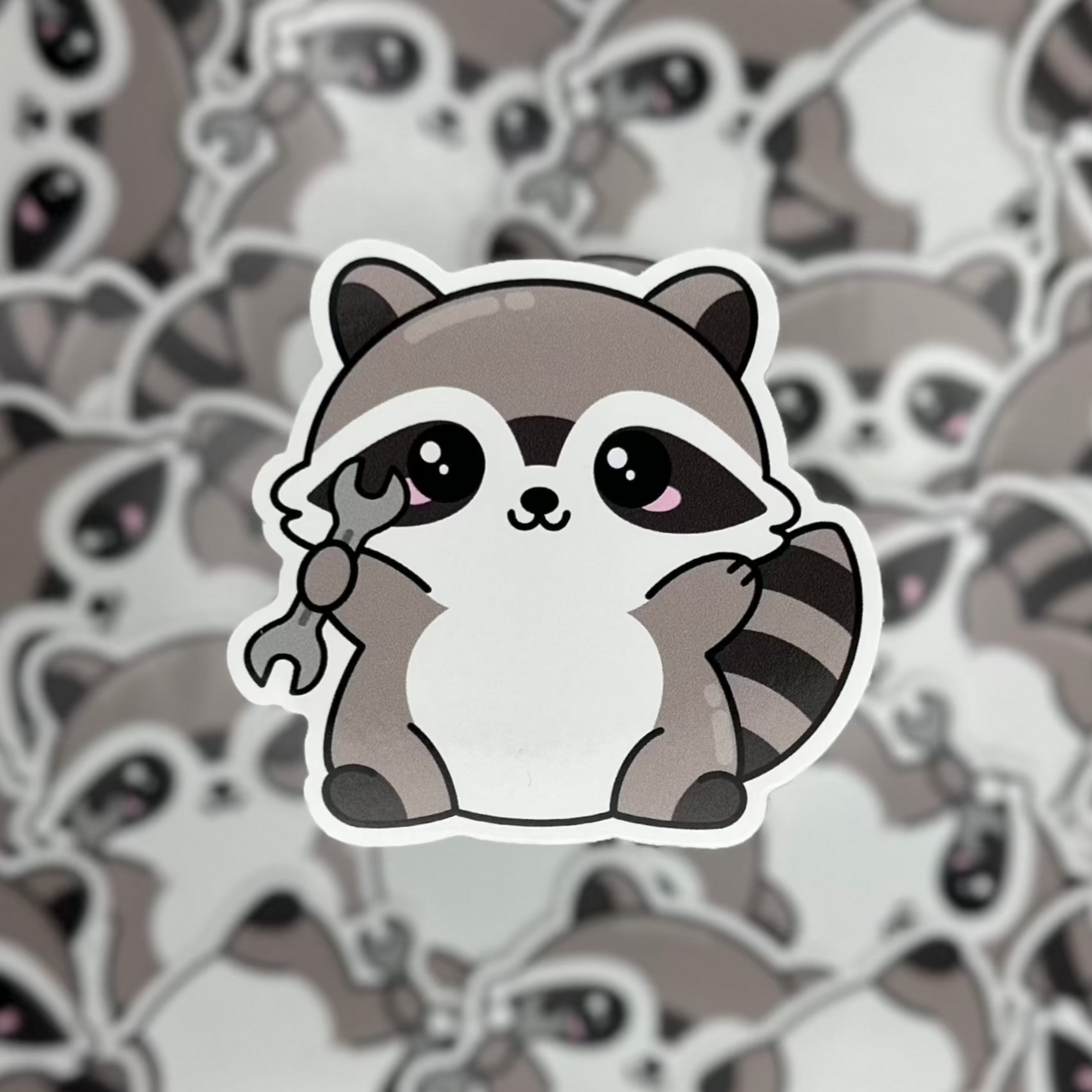 Sticker of a cute raccoon holding a nut on a background of similar raccoon illustrations.