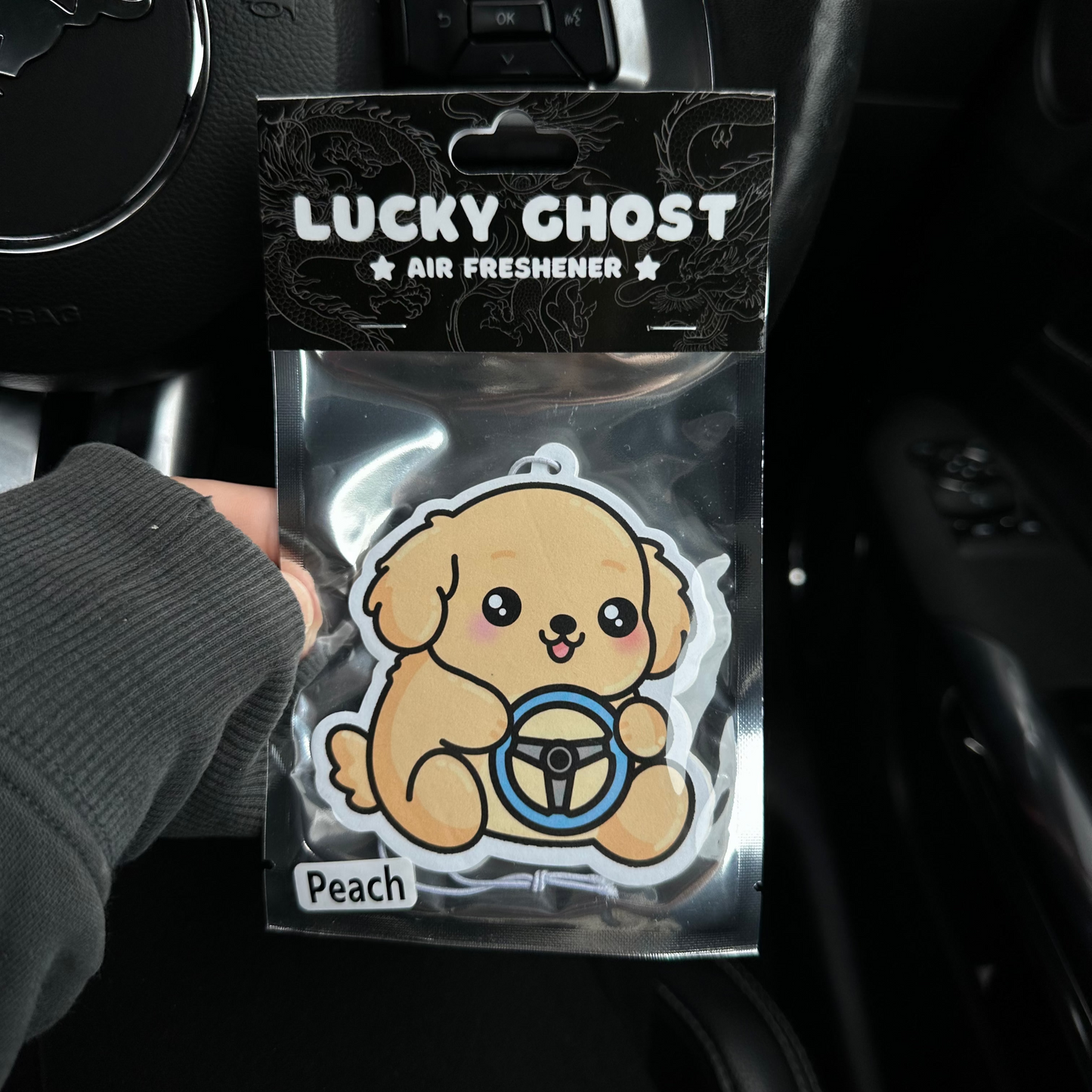 Lucky Ghost air freshener packaging with a cartoon dog character in a car interior.