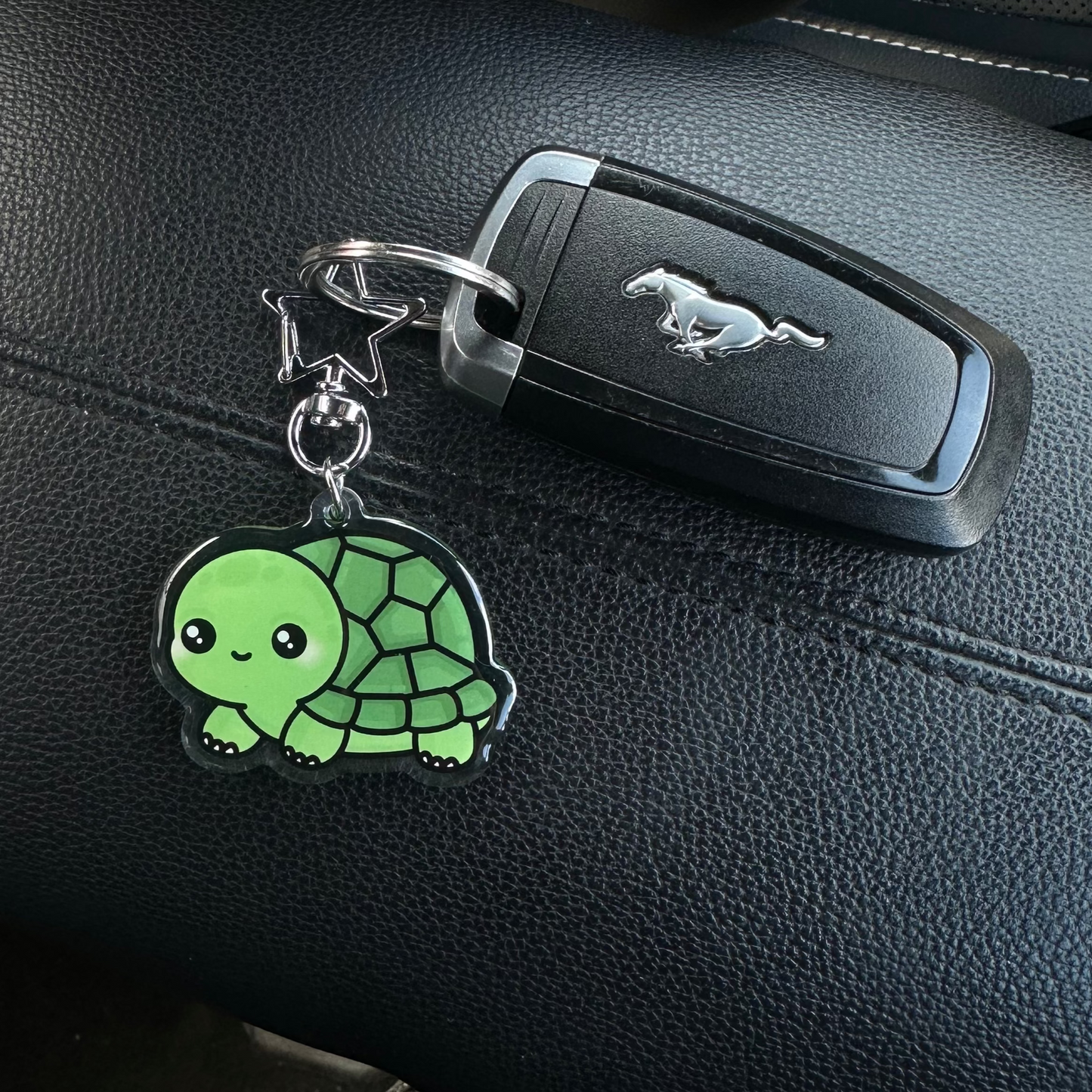 Keychain with a green turtle design on a car seat