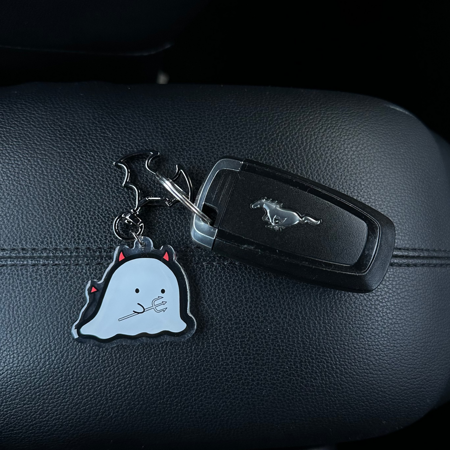 Car key with a keychain shaped like a ghost on a car dashboard.