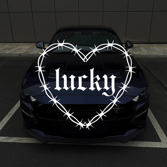 Car with 'lucky' decal in a heart shape with barbed wire on a dark background