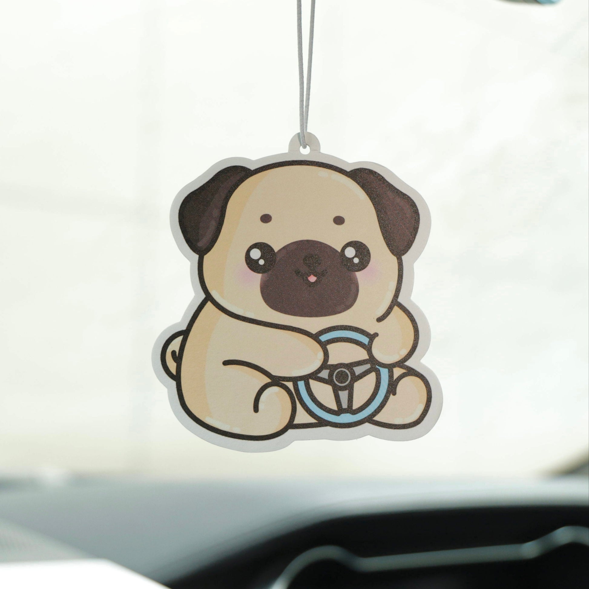 Car air freshener shaped like a pug hanging from a car's rearview mirror.