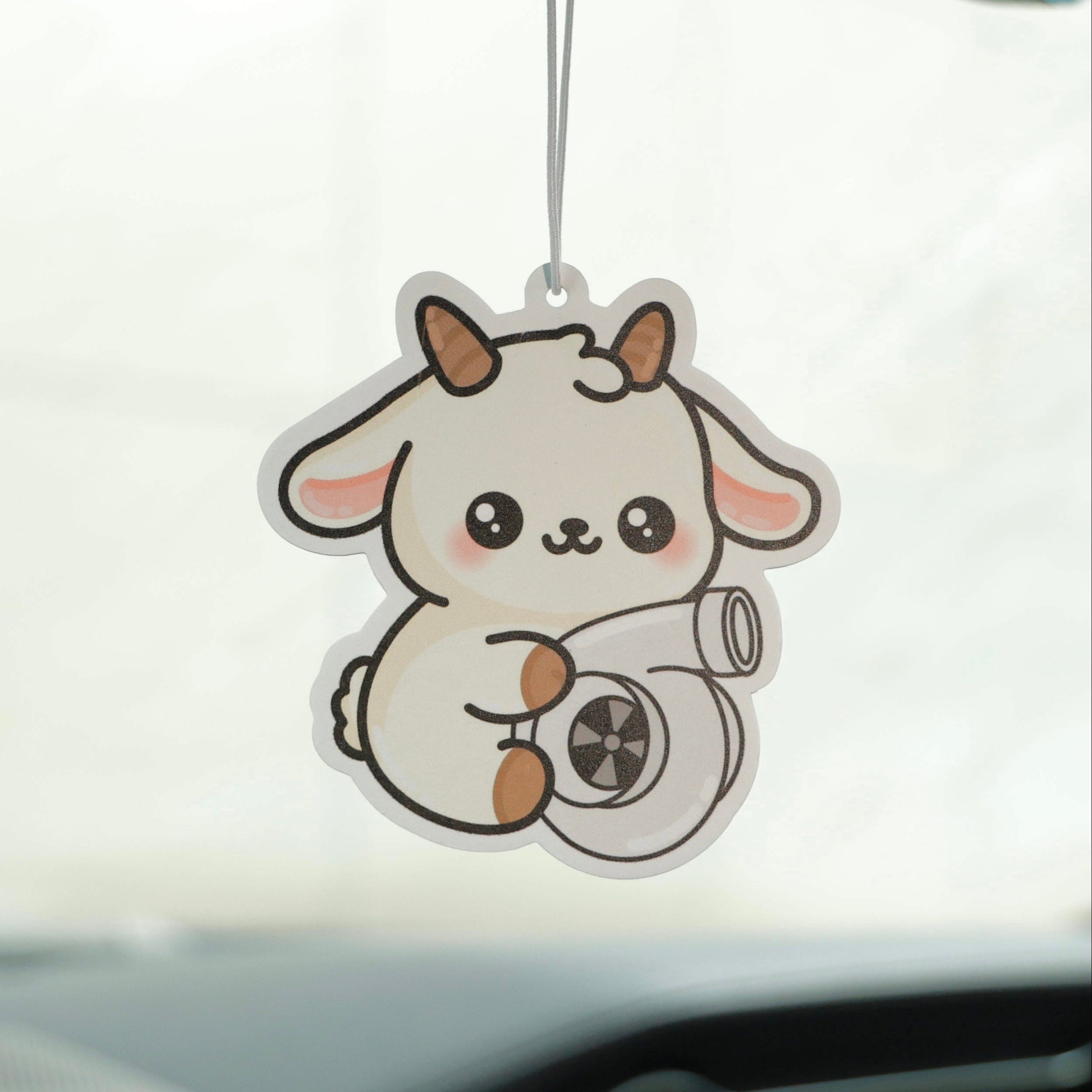 Car air freshener shaped like a goat hanging from a car's rearview mirror.