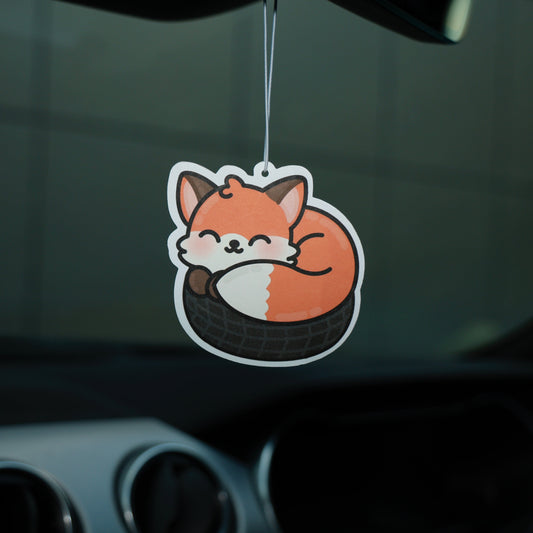 Car air freshener shaped like a fox hanging from a car's rearview mirror.