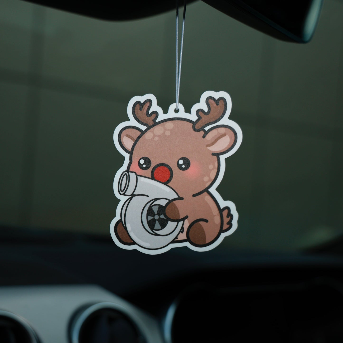 Car air freshener shaped like a cartoon reindeer holding a camera inside a car.