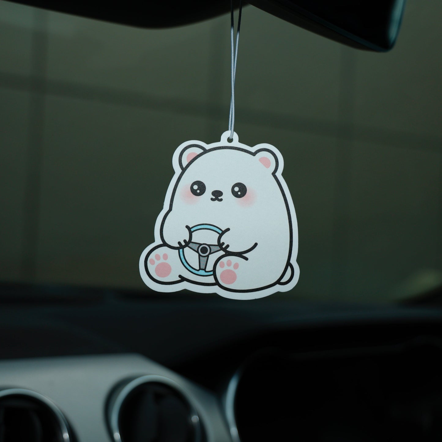 Cartoon bear air freshener hanging from a car's rearview mirror.