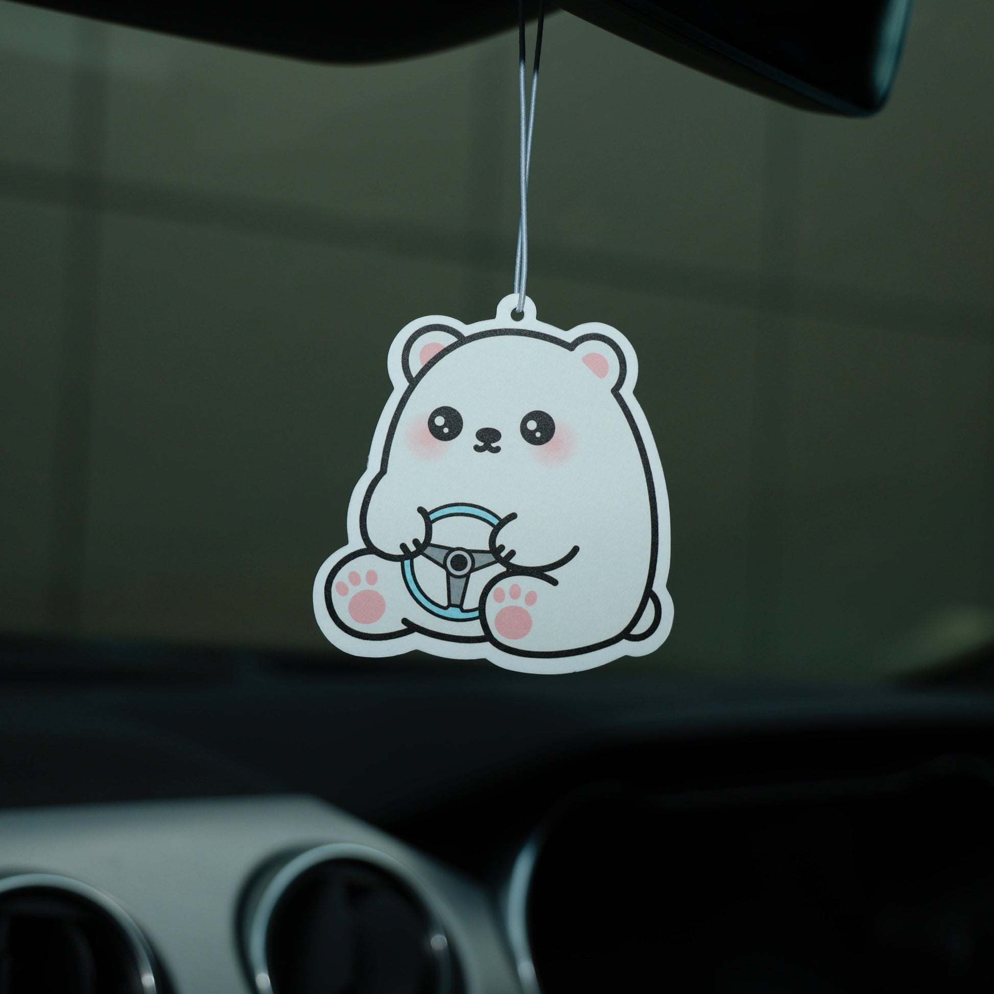 Cartoon bear air freshener hanging from a car's rearview mirror.