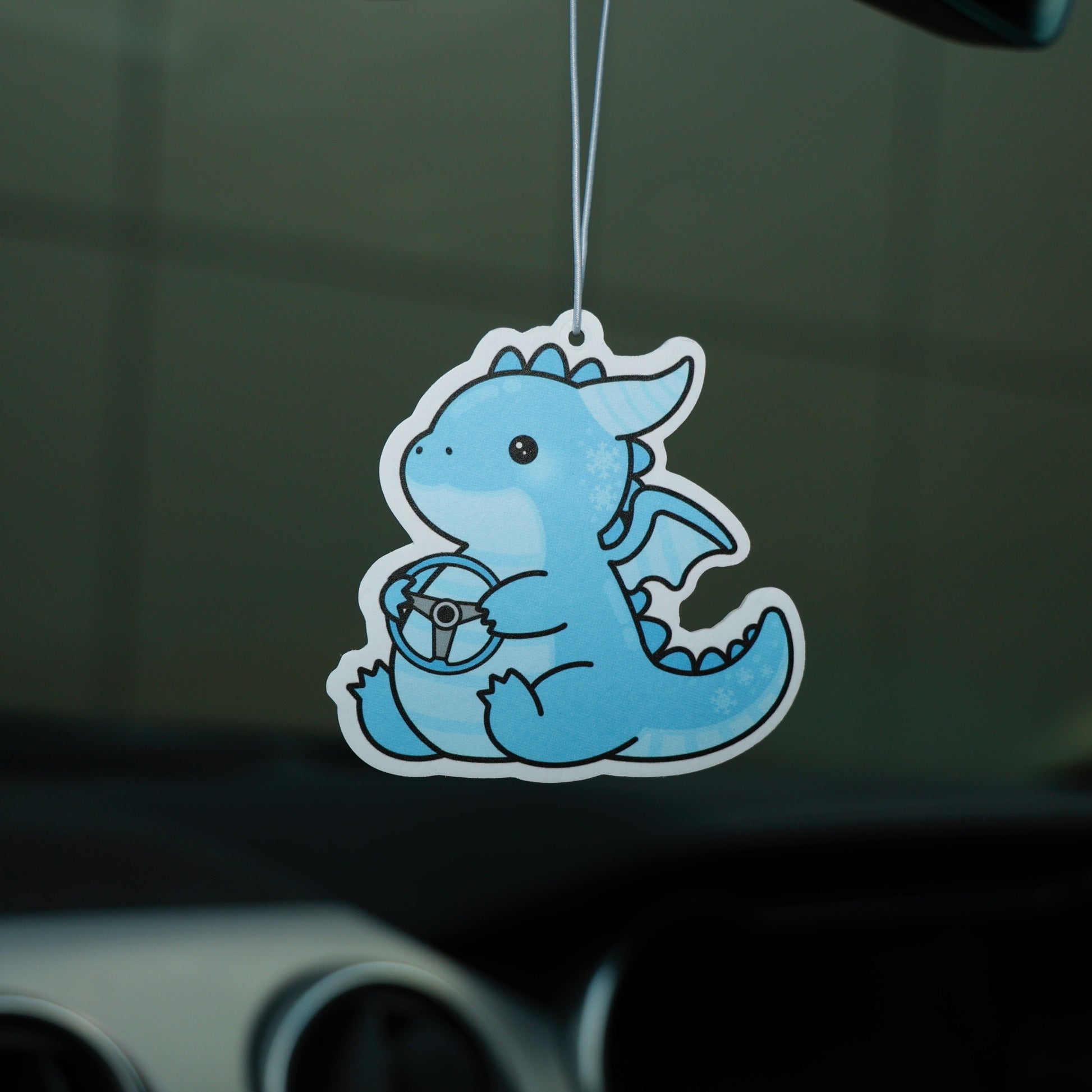 Blue dragon-shaped air freshener hanging from a car's dashboard.