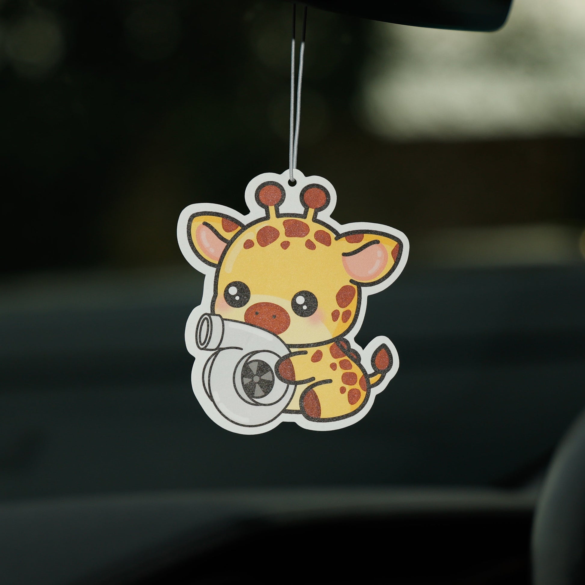 Car air freshener shaped like a giraffe hanging from a car's rearview mirror.
