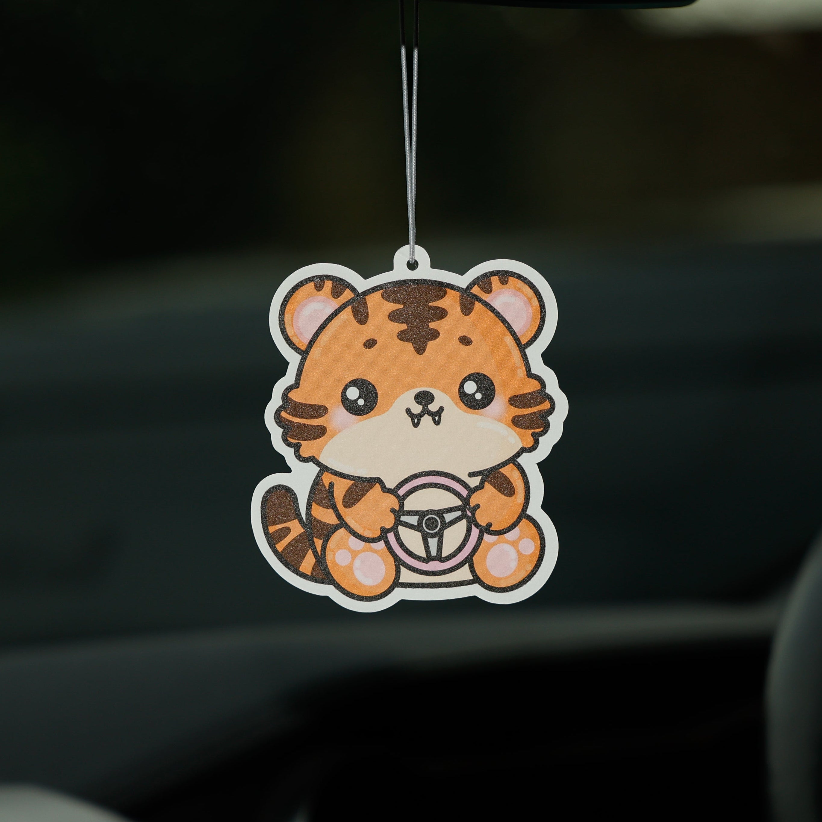 Car air freshener shaped like a tiger hanging from the rearview mirror.