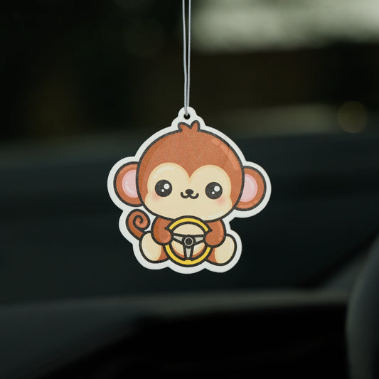Car air freshener shaped like a monkey hanging from a car's rearview mirror.
