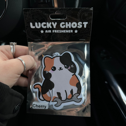 Lucky Ghost air freshener packaging held by a hand inside a car.