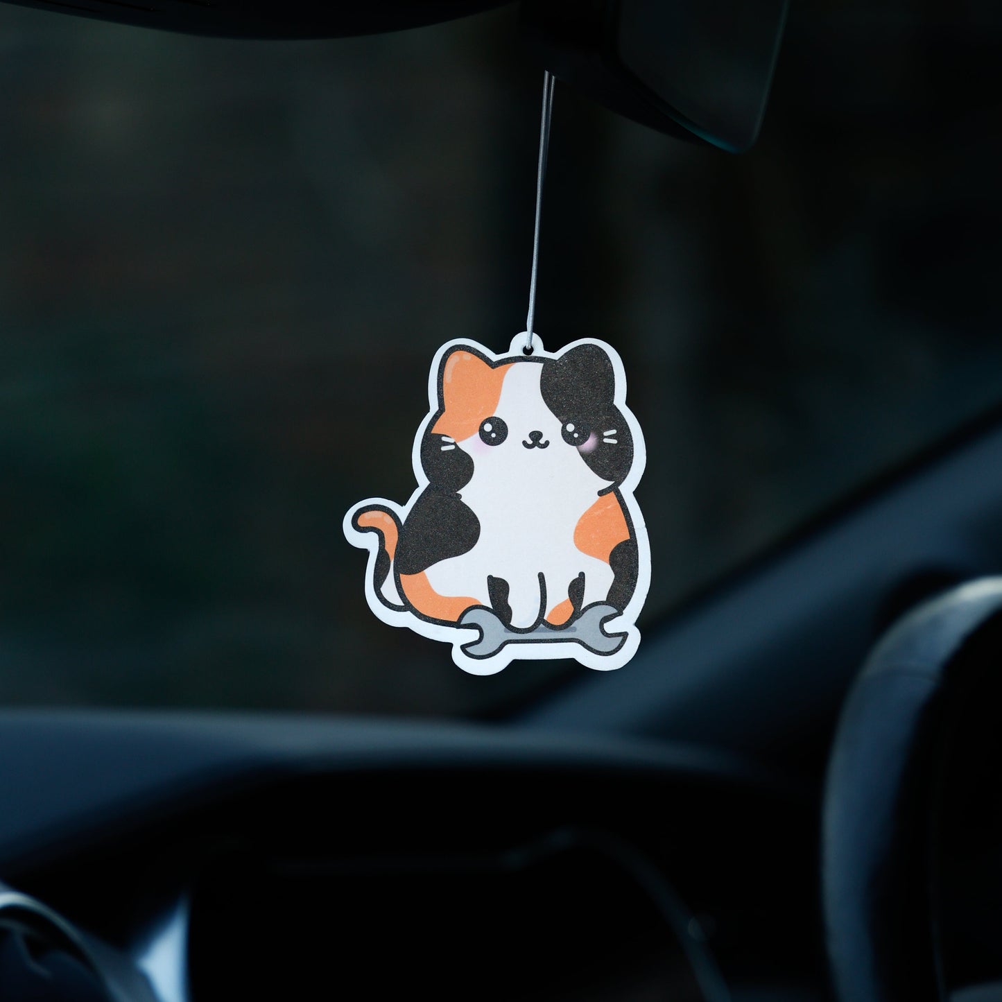 Car air freshener shaped like a cat hanging from the rearview mirror.