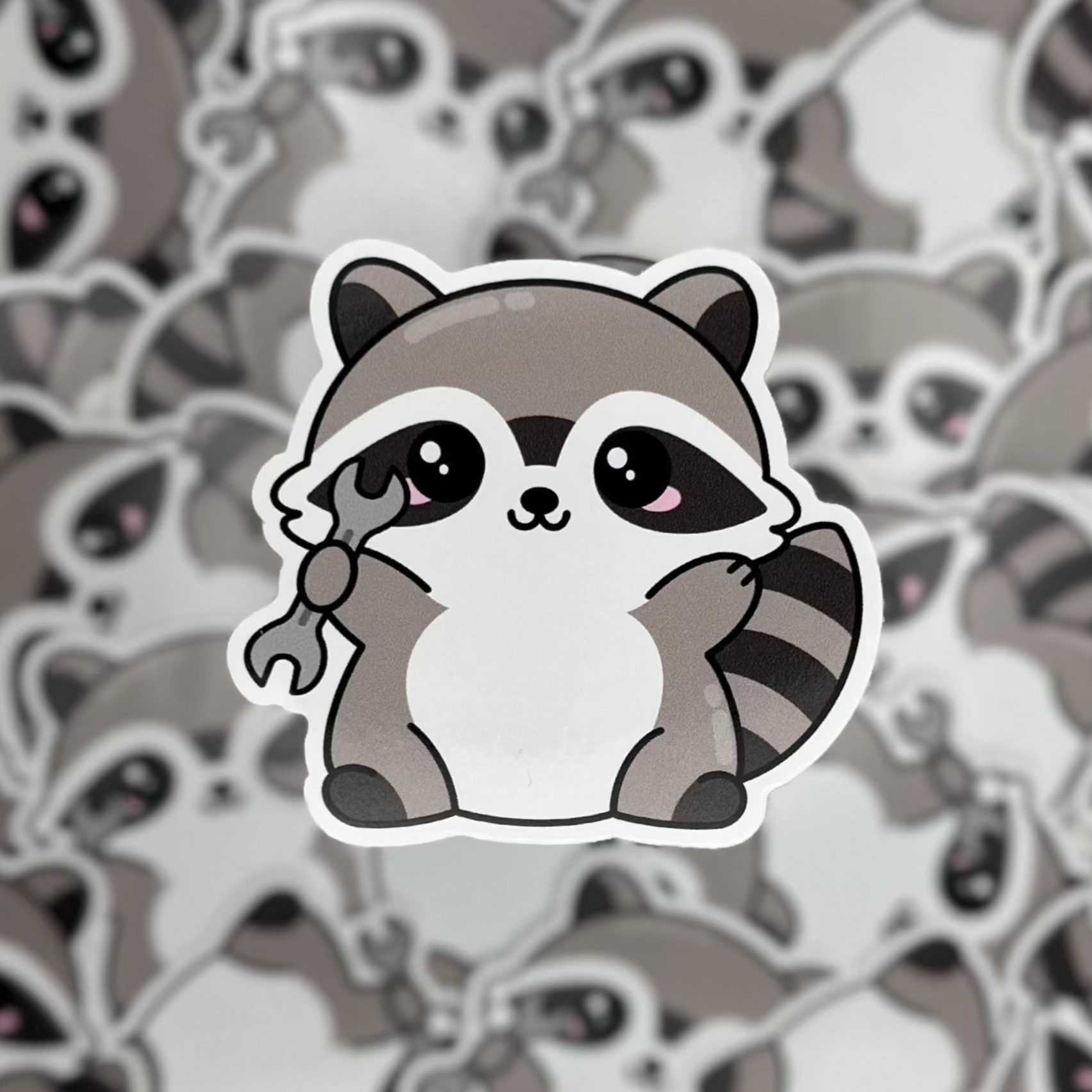 Sticker of a cute raccoon holding a nut on a background of similar raccoon illustrations.