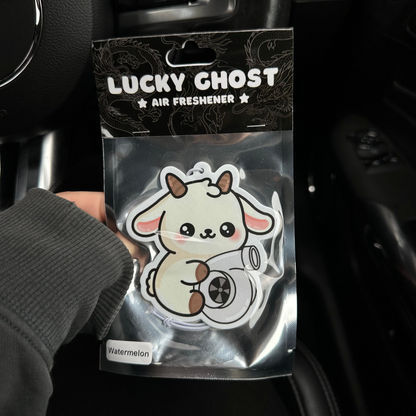 Lucky Ghost air freshener packaging held by a hand inside a car.
