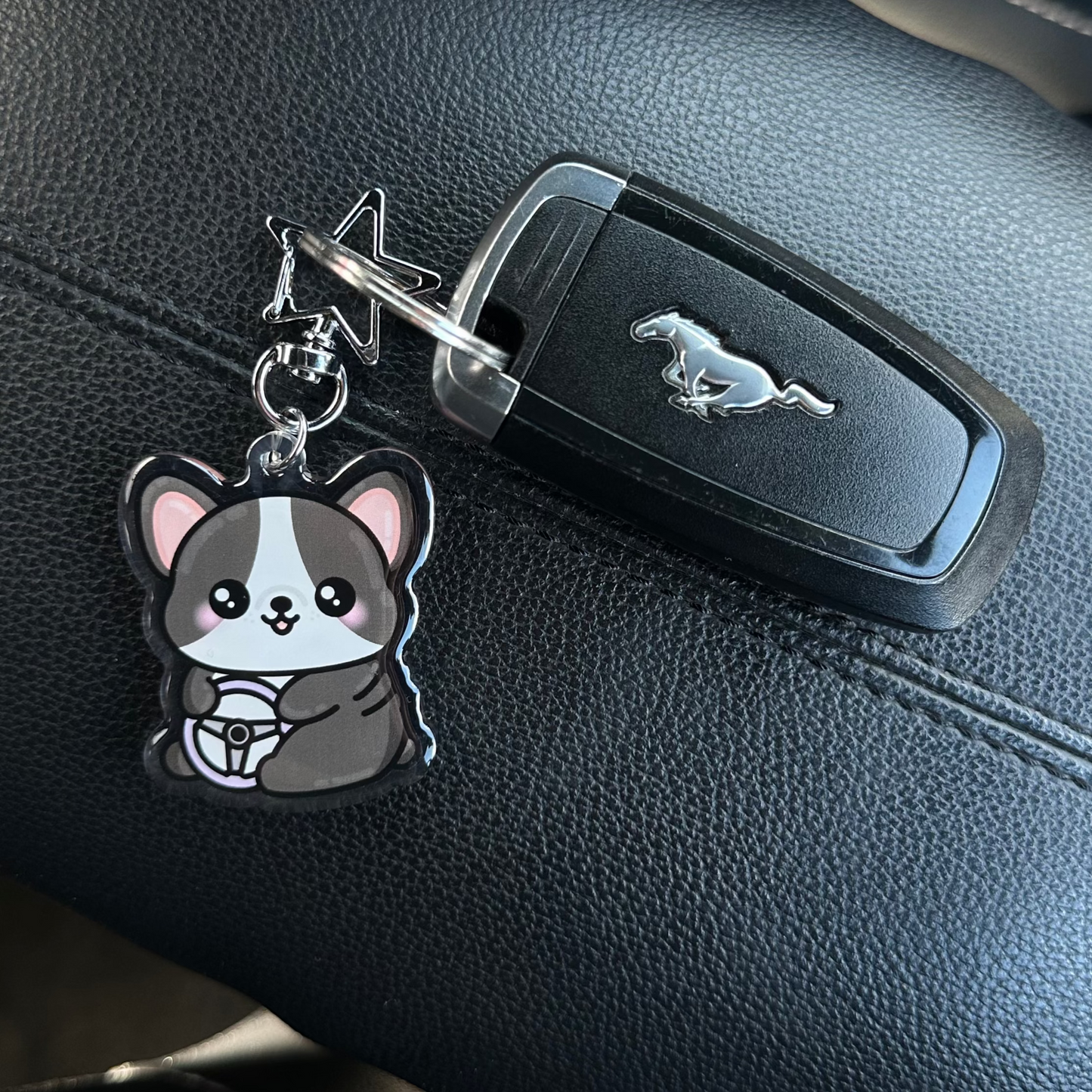 Car key with a cute animal-shaped keychain attached, placed on a car seat.