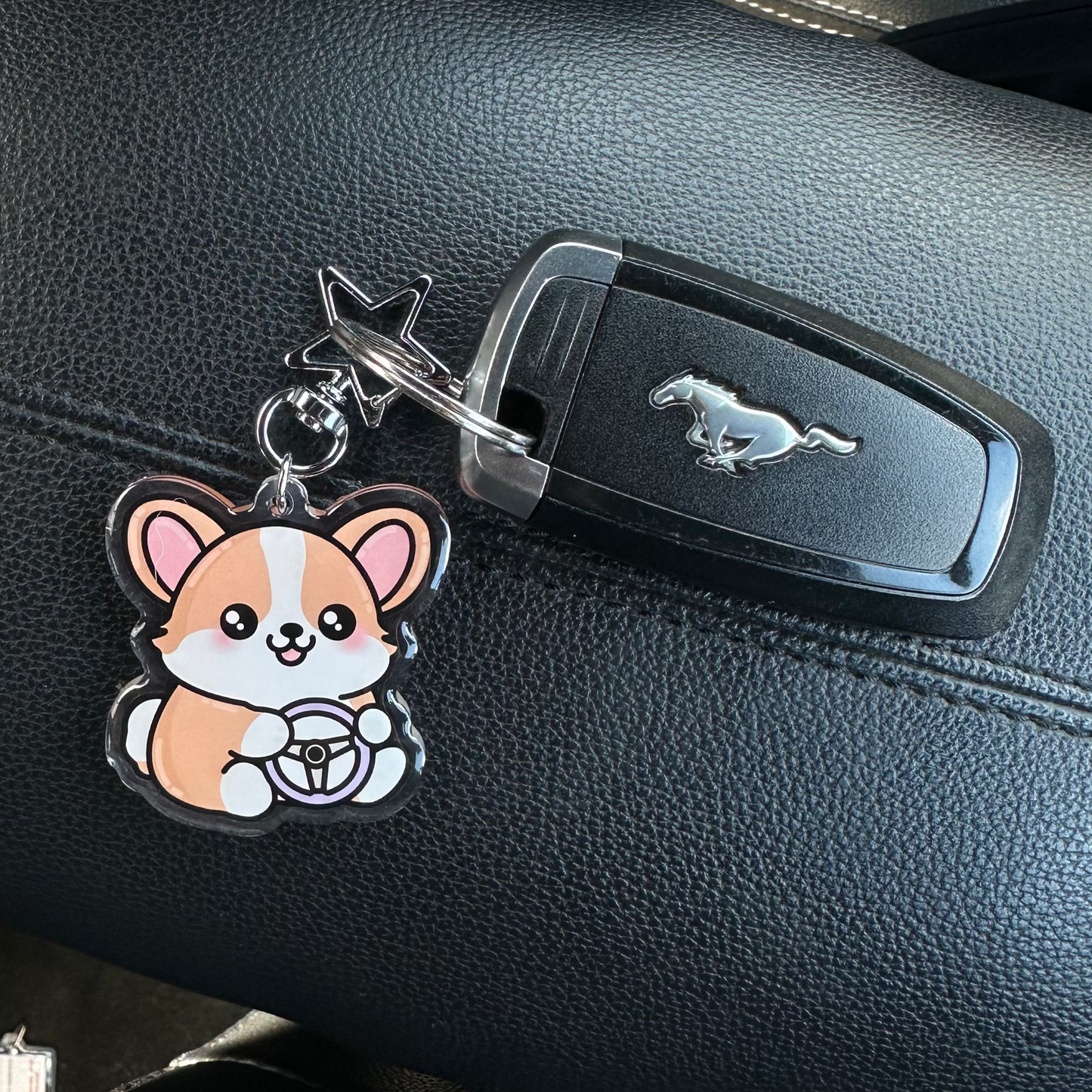 Car key with a keychain shaped like a cartoon dog on a car dashboard.