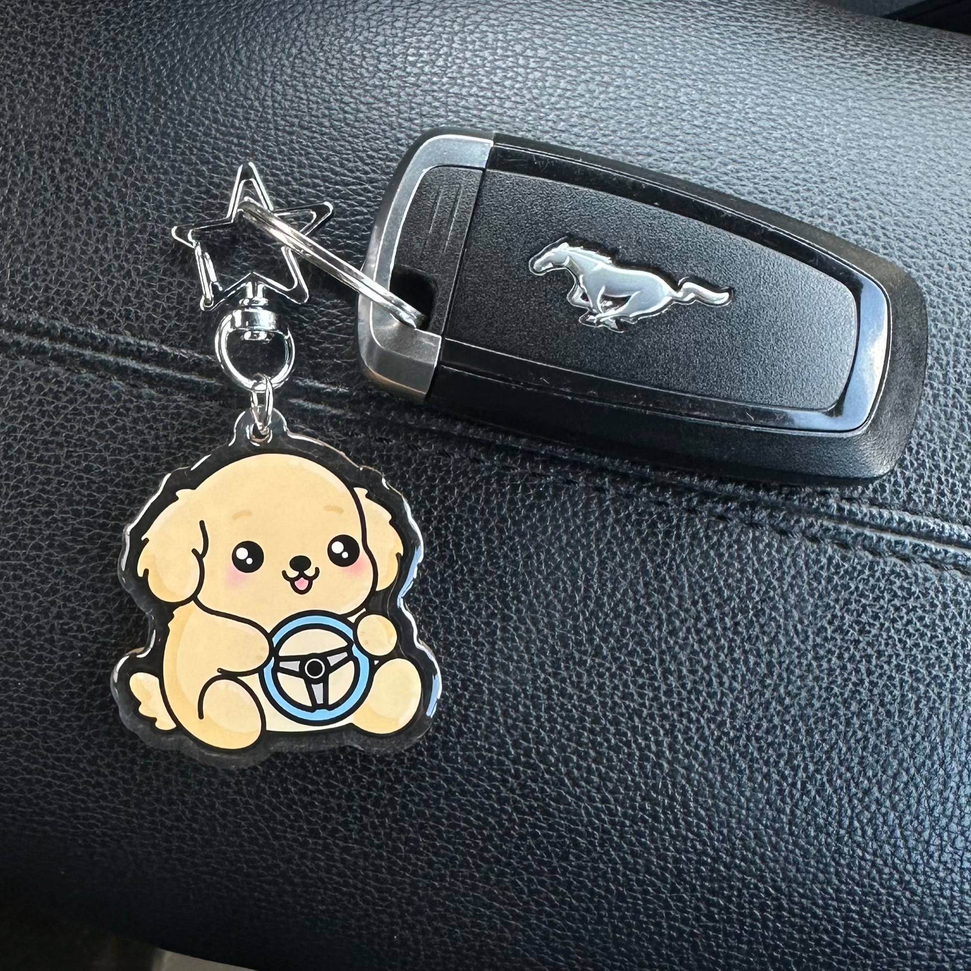 Car key with a dog-shaped charm on a black leather car seat.