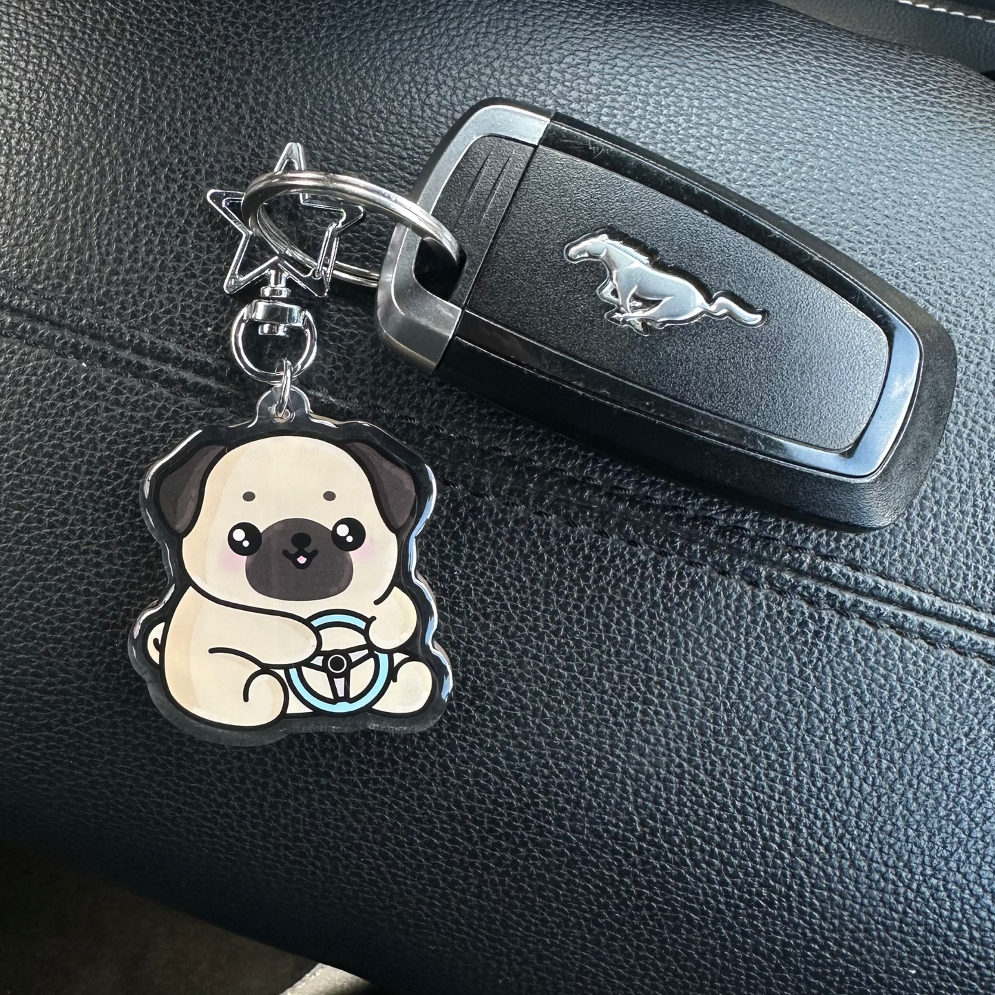 Keychain with a dog design attached to a car key on a car dashboard.