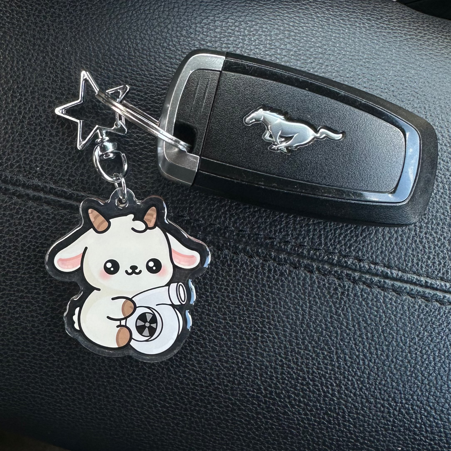 Keychain with a cute design on a car dashboard with a visible brand emblem.