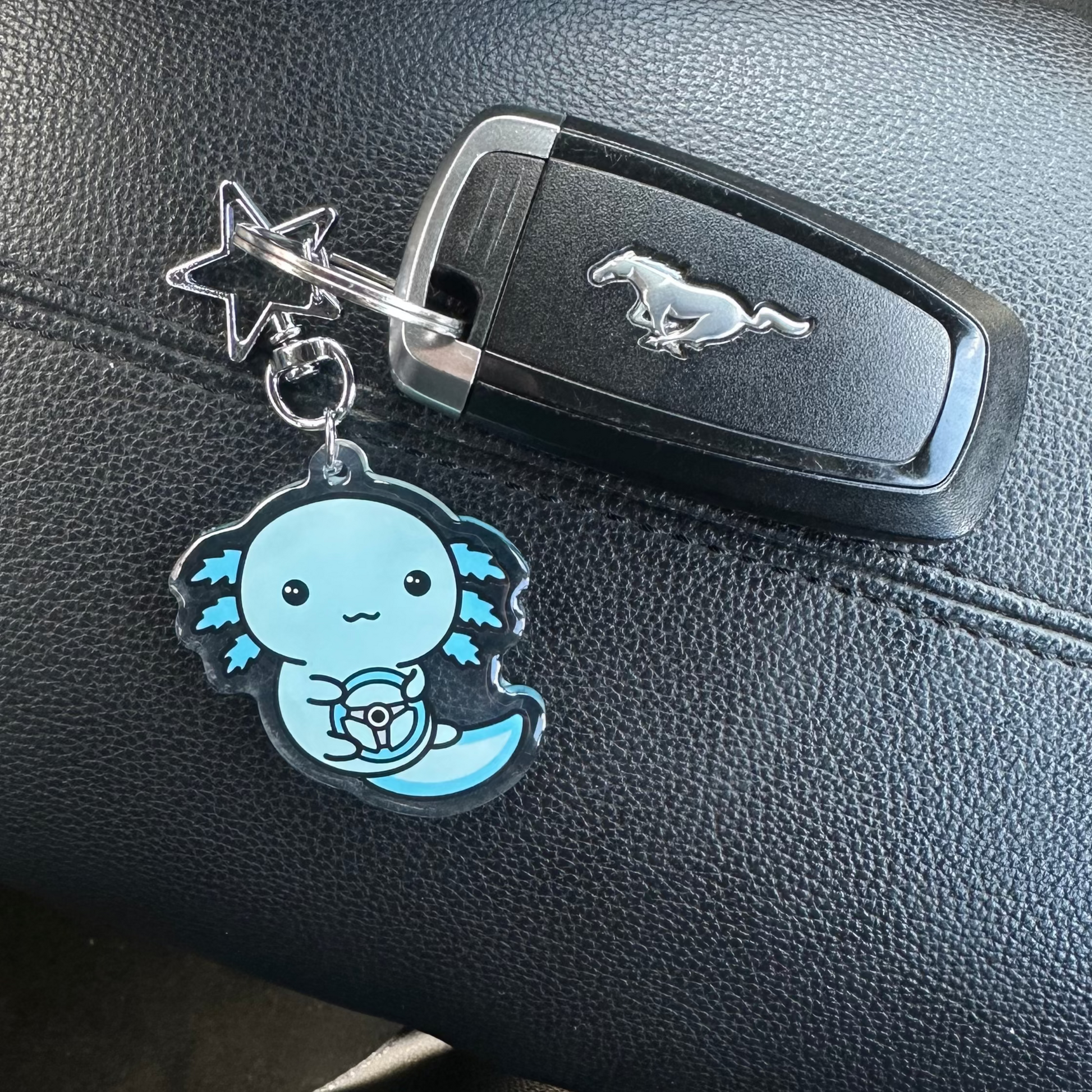 Car key with a keychain featuring a blue character on a car dashboard.