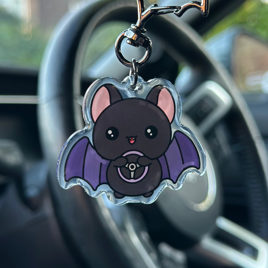 Kawaii-style bat keychain hanging from a car's keychain holder.