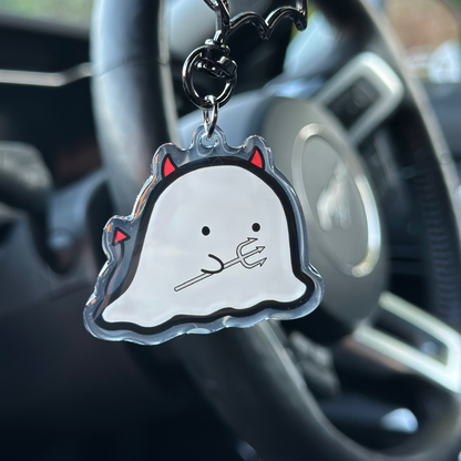 Ghost-shaped keychain with red accents hanging from a car's keychain holder.