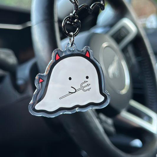 Ghost-shaped keychain with red accents hanging from a car's keychain holder.