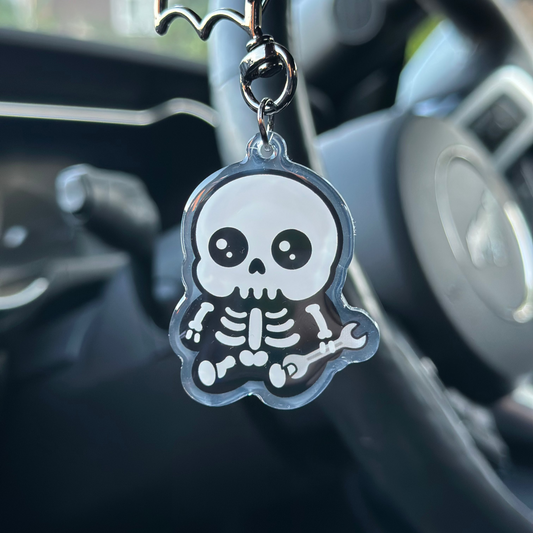 Skull and bat keychain hanging from a car's rearview mirror.
