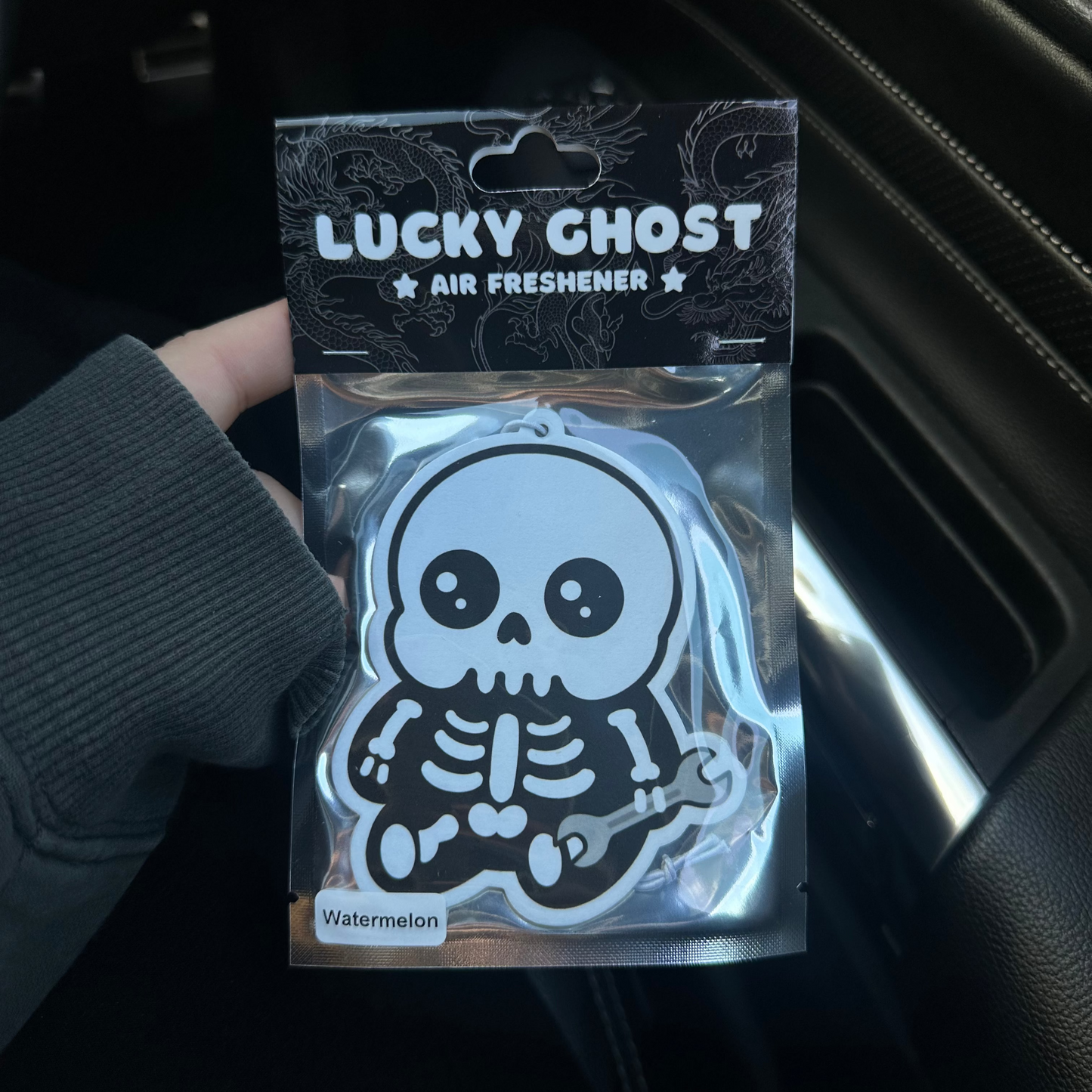 Lucky Ghost air freshener packaging held inside a car.