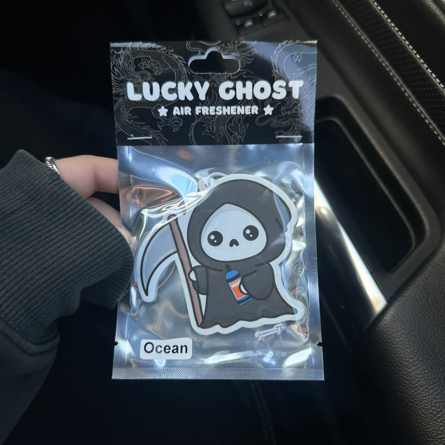 Air freshener packaging with a cartoon ghost design held by a person.