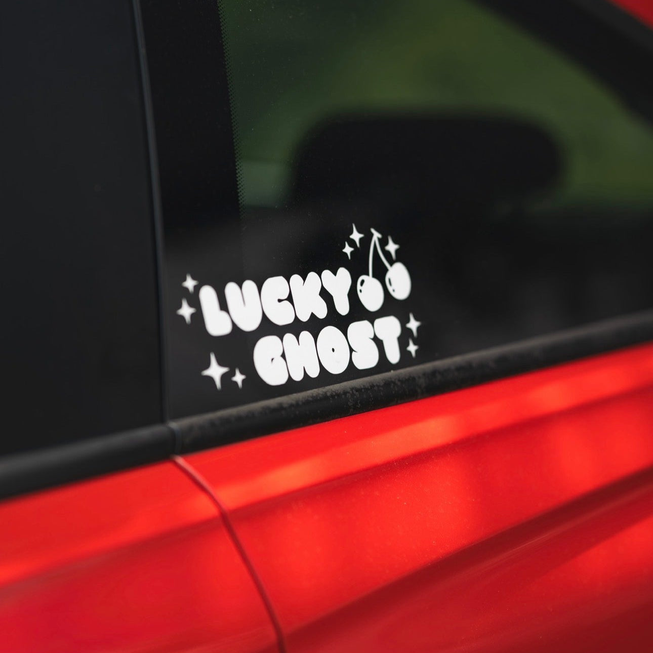 Sticker with 'Lucky Ghost' text on a car window