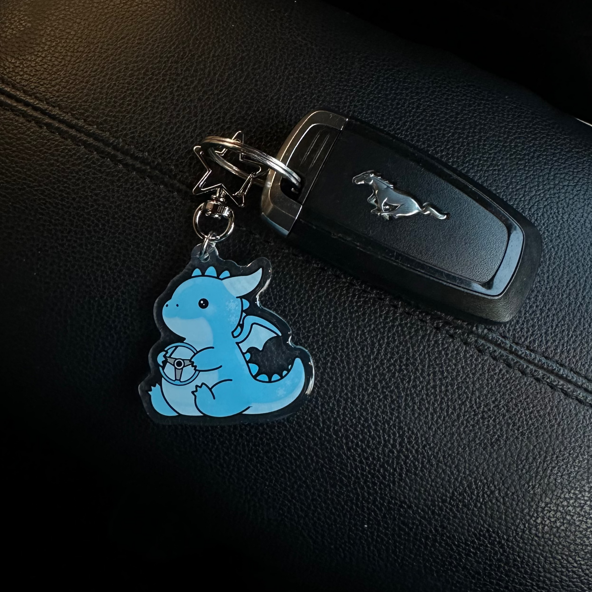 Keychain with a blue cartoon character attached to a car key on a black leather surface.