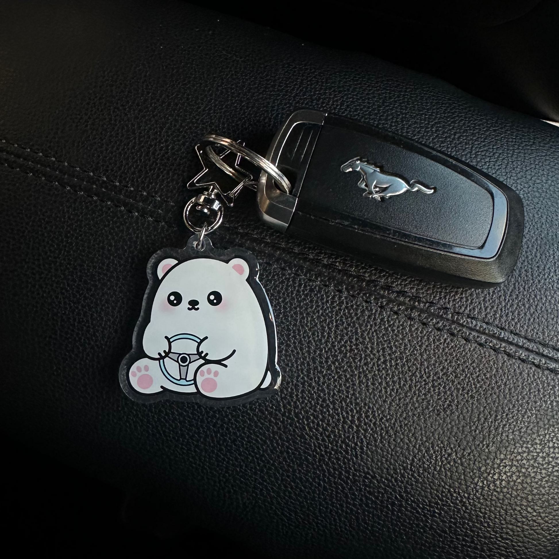 Keychain with a cartoon character attached to a car key on a black leather surface.