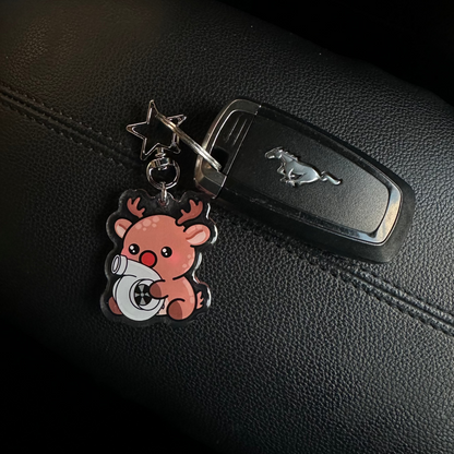 Car key with a keychain featuring a bear holding a heart on a black car dashboard.