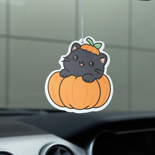 Car air freshener with a black cat on a pumpkin in a car interior.