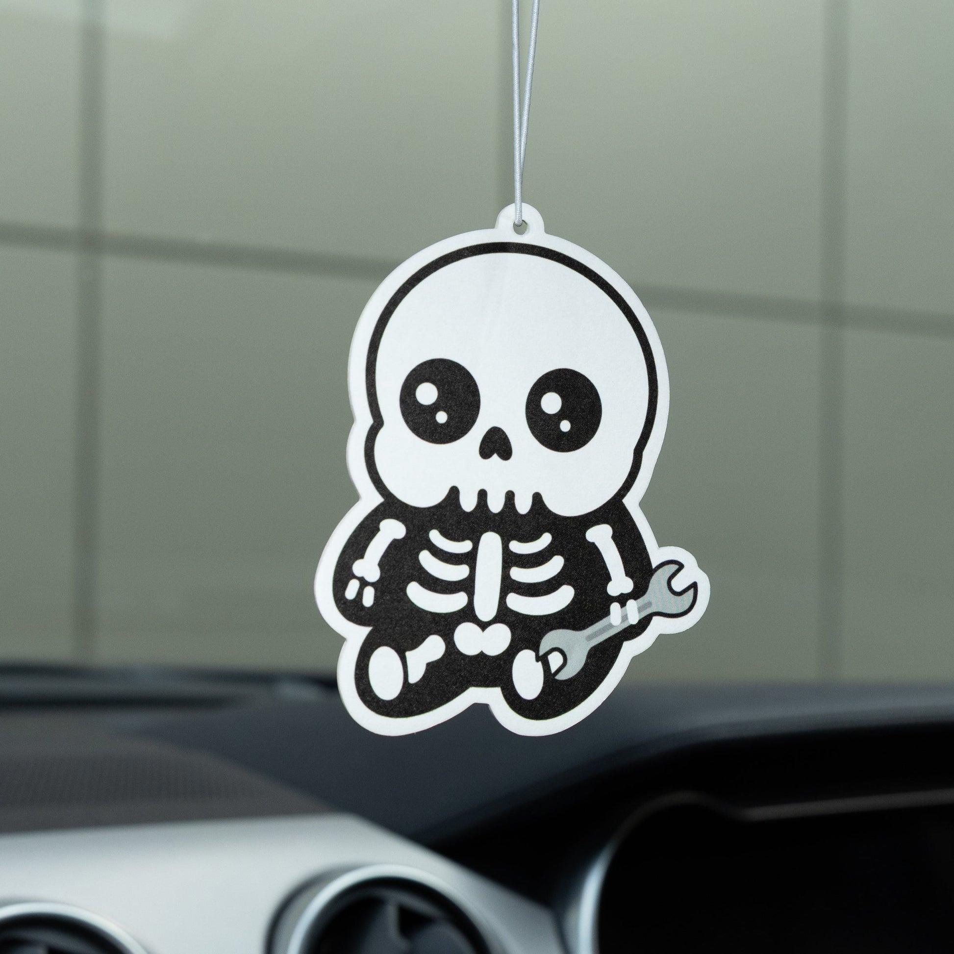 Car air freshener with a skeleton design hanging from the rearview mirror.
