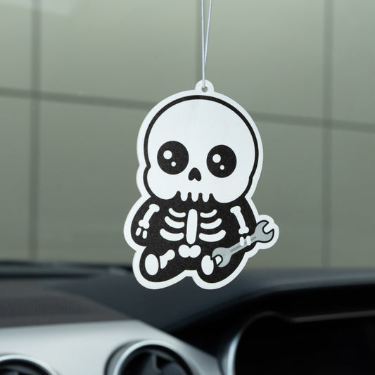 Car air freshener with a skeleton design hanging from the rearview mirror.