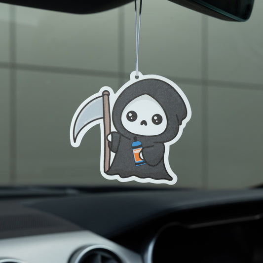 Car air freshener shaped like a cute grim reaper character hanging from a car's rearview mirror.