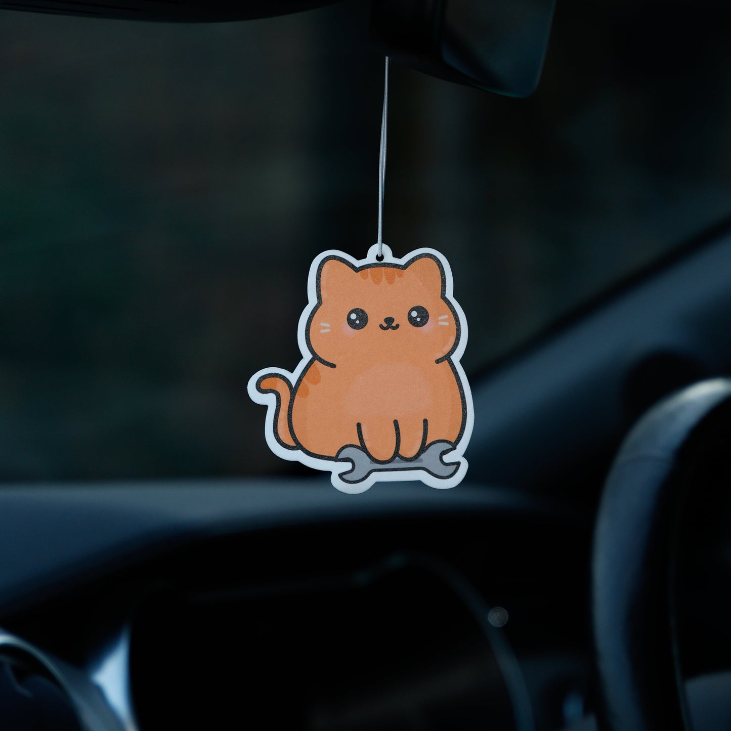 Car air freshener shaped like a cat hanging from the rearview mirror.
