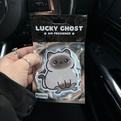 Lucky Ghost air freshener packaging held in a car interior