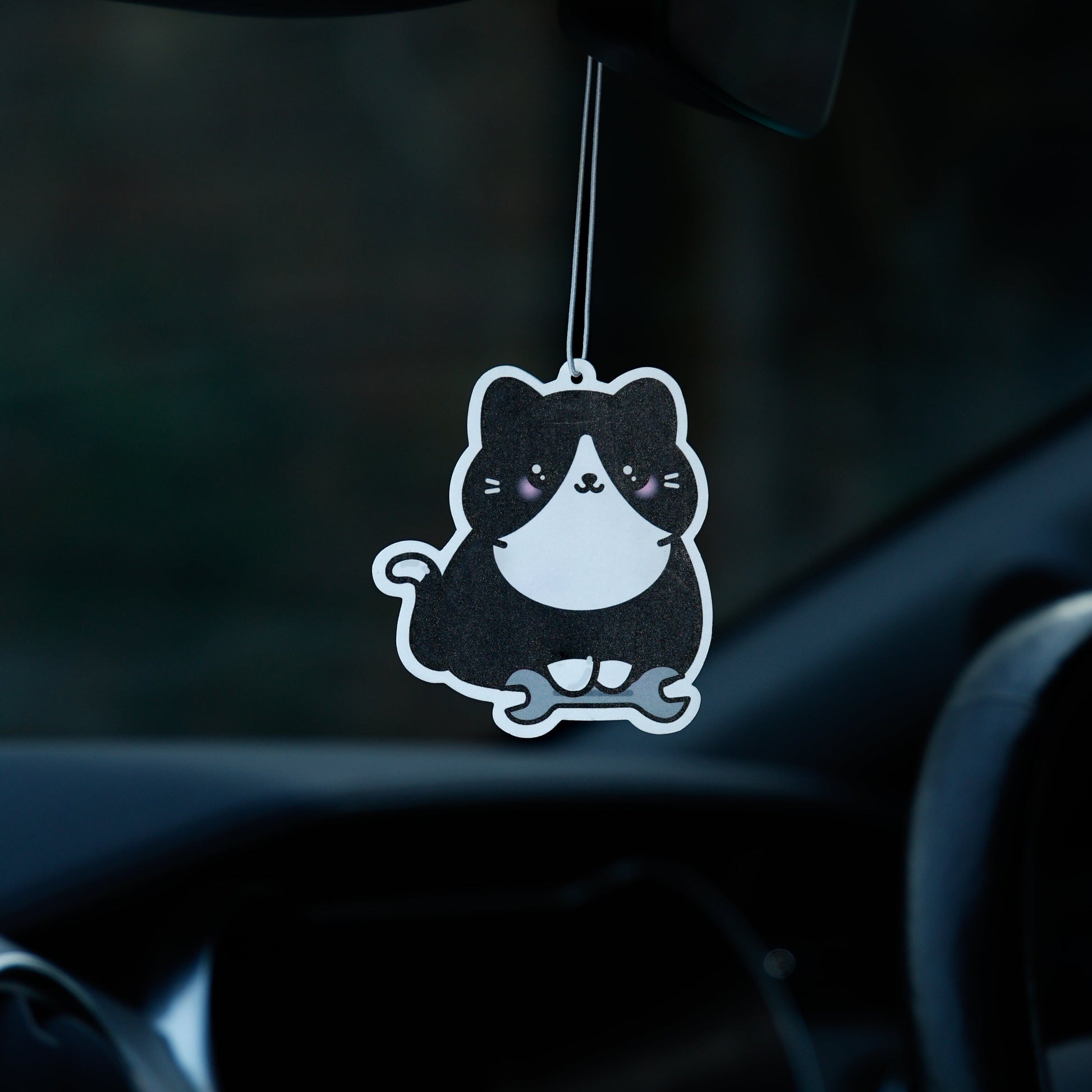 Car air freshener shaped like a cat hanging from the rearview mirror.